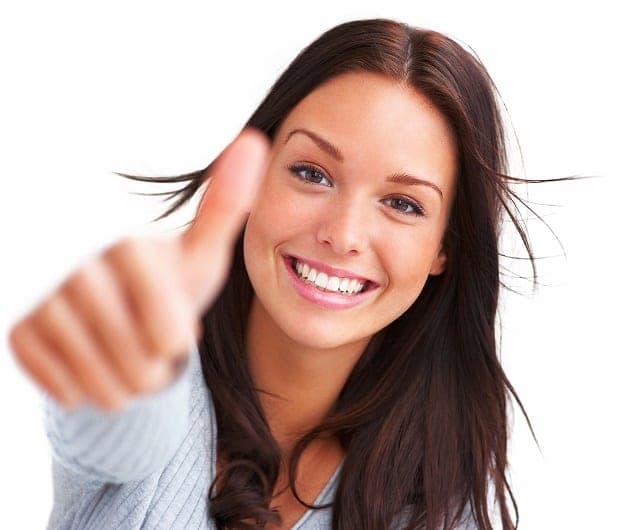 Smiling brunette woman giving an enthusiastic thumbs-up against a white studio backdrop