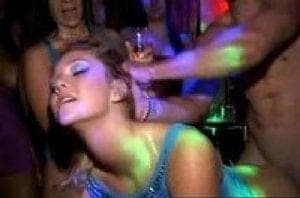 Woman in a blue sequined top at a nightclub with neon lighting, eyes half closed as others crowd around