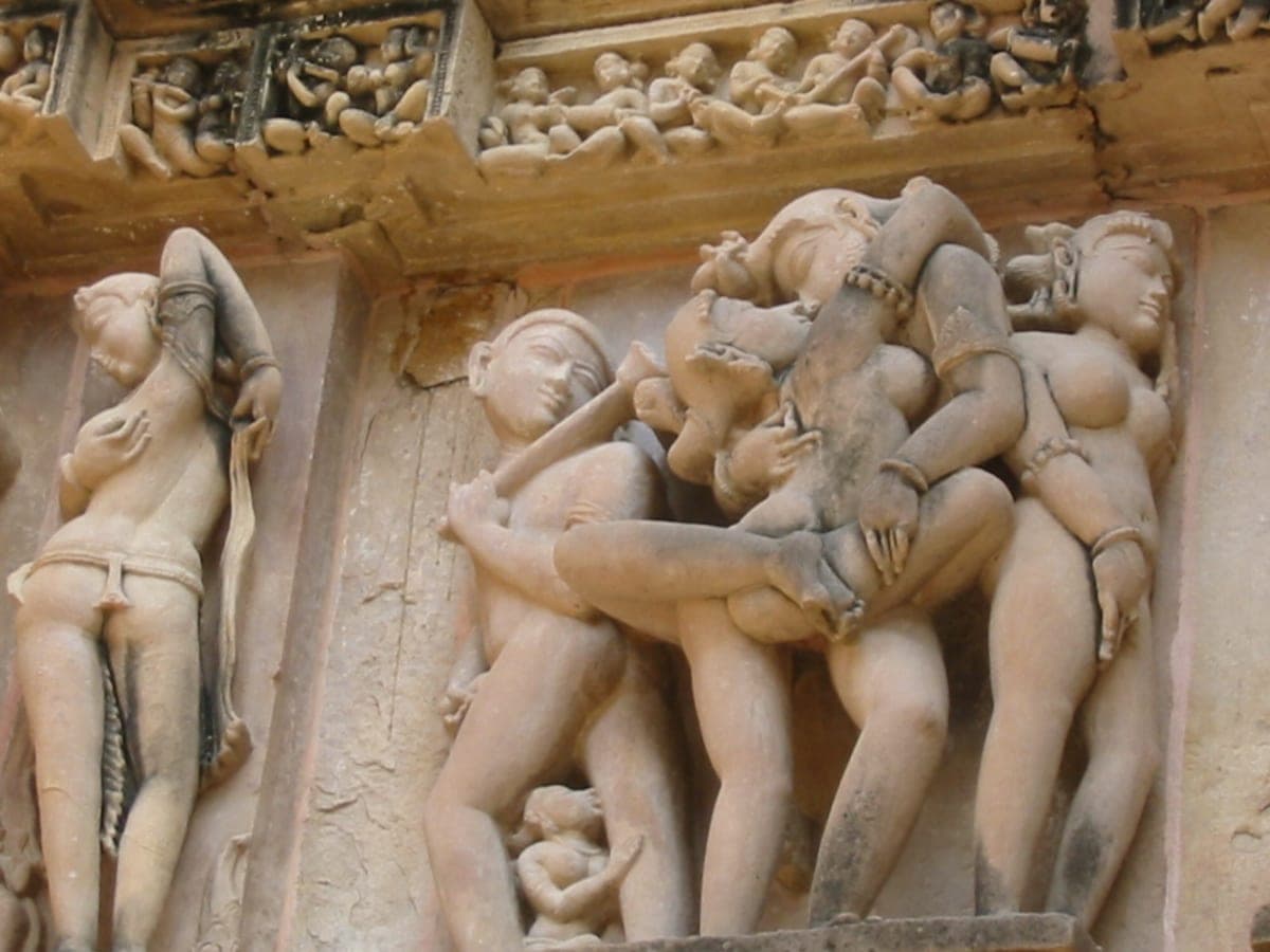 Weathered stone temple carvings of intertwined nude figures in intimate poses, Khajuraho-style relief