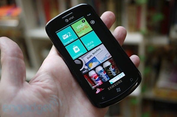 Hand holding a black Samsung Windows Phone displaying colorful tile-based home screen