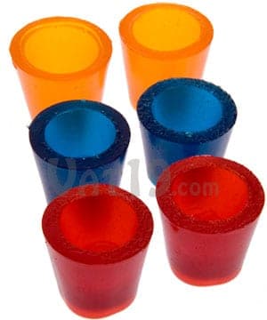 Six brightly colored gummy shot glasses in orange, blue, and red arranged in a cluster on a white surface
