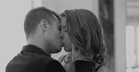 Black-and-white close-up of a man and woman kissing softly, faces pressed together in profile